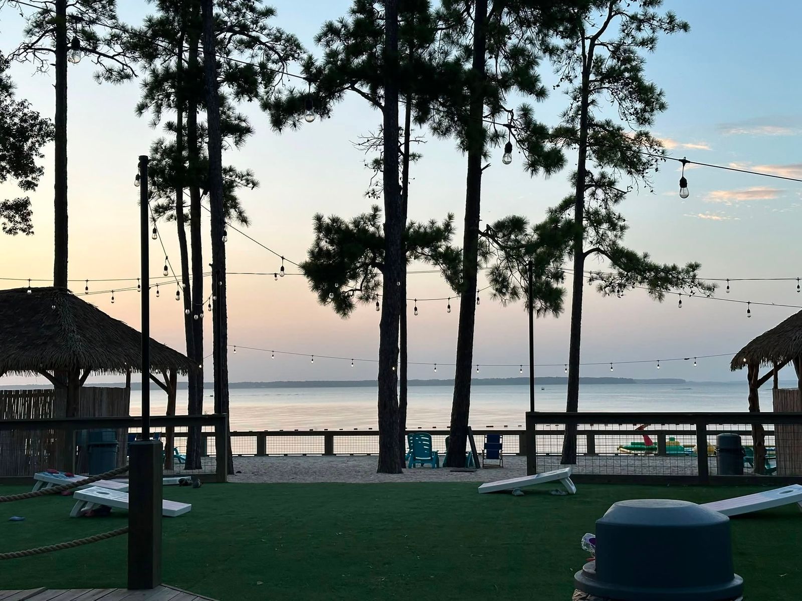 The lakefront facility at dusk, boats moored at the dock and tall pines framing the calm water.