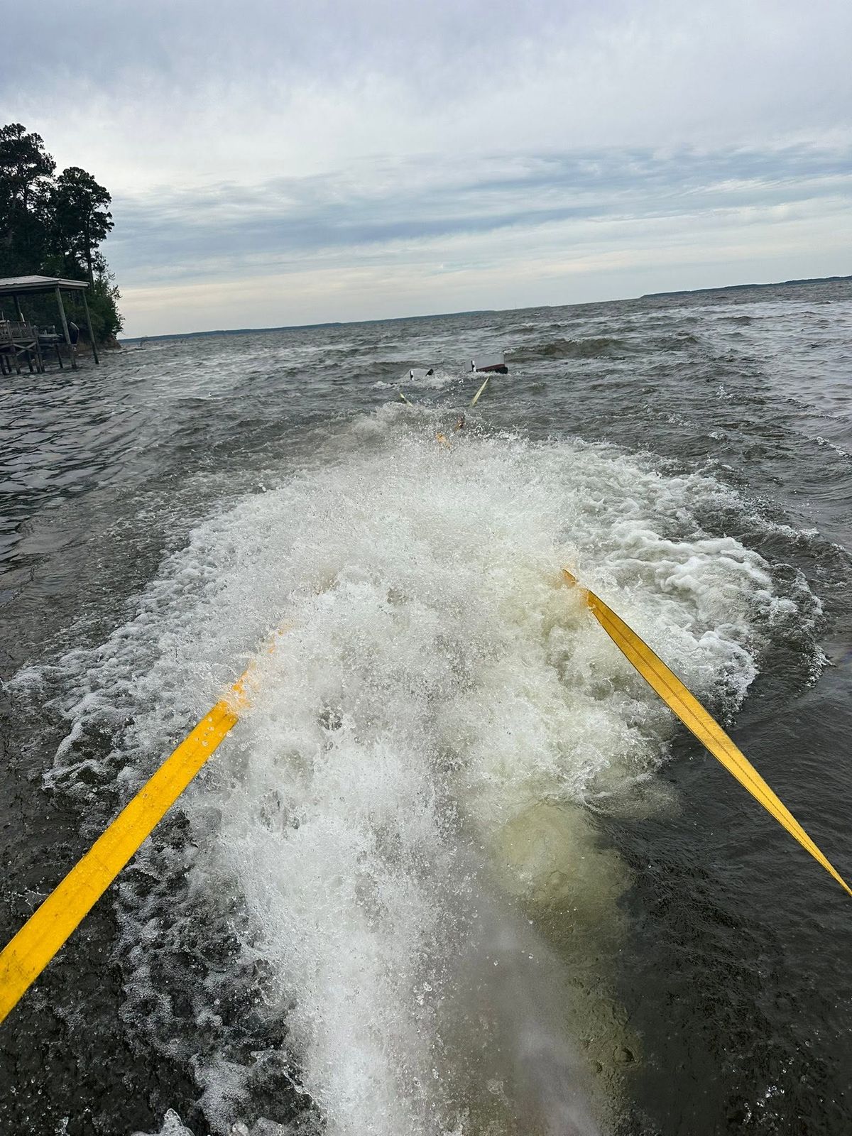 A TowBoatUS Sam Rayburn boat throwing a wake as it heads out onto the reservoir, towing equipment on the deck in the foreground.