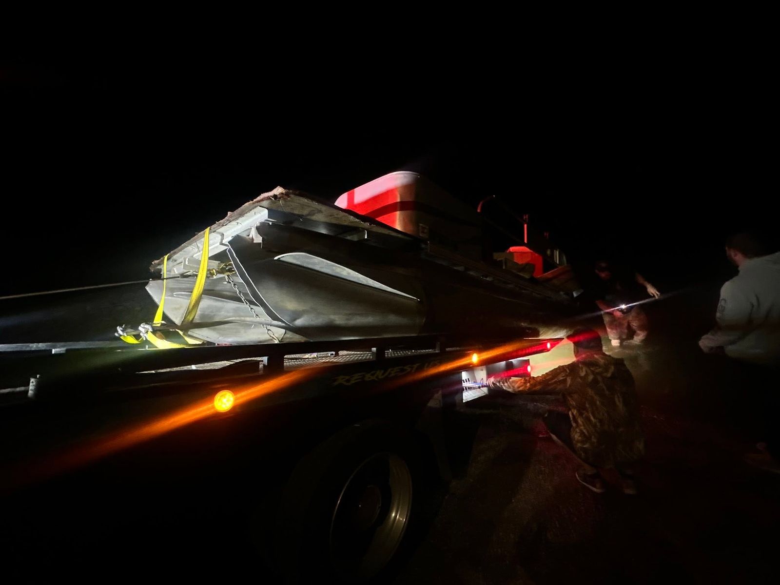 A towing vessel at night with recovery equipment secured on the deck.